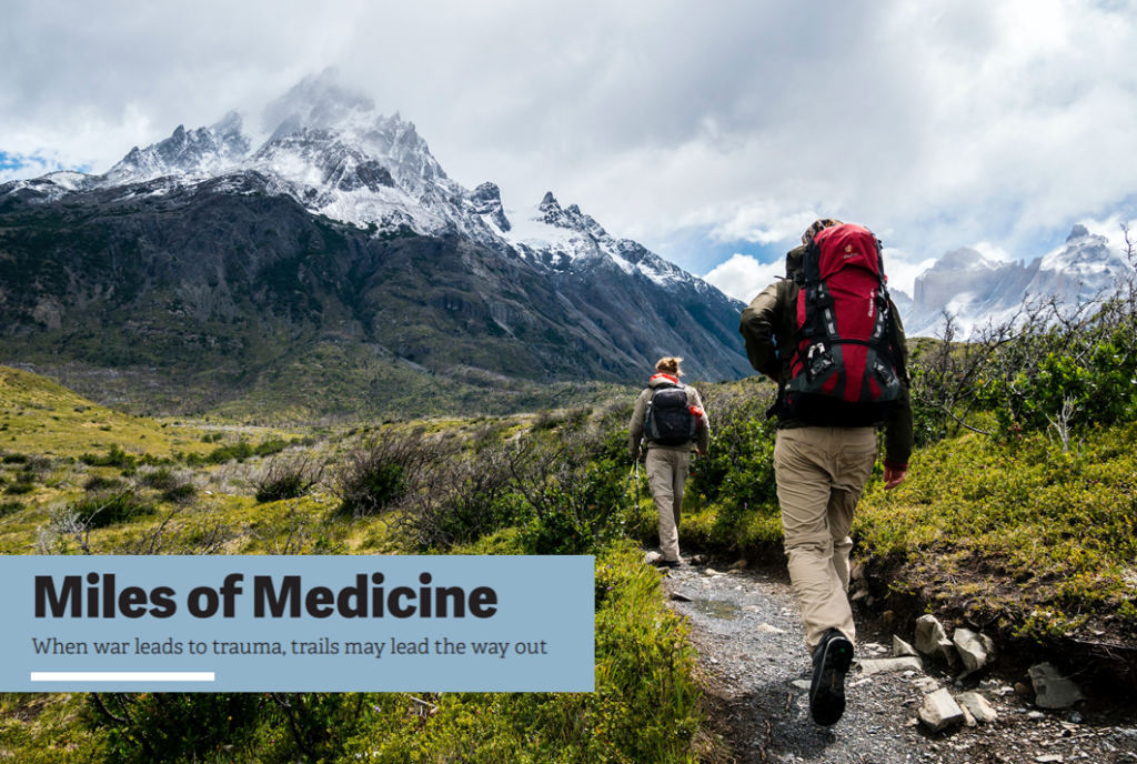 Two hikers with rocks and mountains in the background