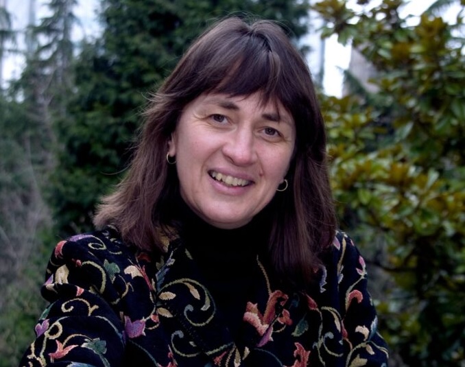 A headshot of Kathy smiling with trees in the background