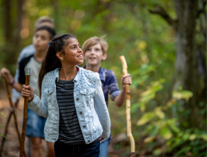 Four children hiking in a deciduous forest