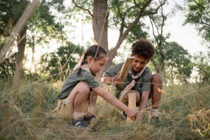 Two scouts are outdoors and building with pieces of wood
