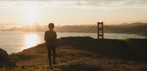 A person hikes with the Golden Gate Bridge in the background.