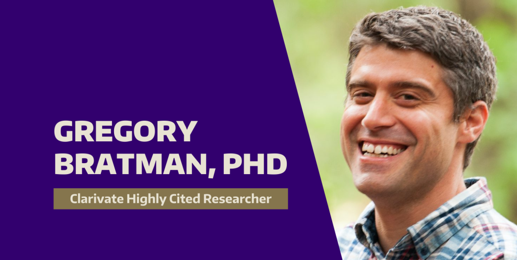 Gregory Bratman smiles widely. A forest is in the background.