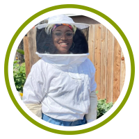 Ivy wears a beekeeping suit and smiles