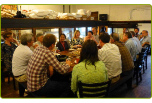 Participants in the first Nature and Health Community Dinner talk around a large table at Ravenna Brewery