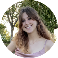 A headshot of Maya smiling with trees in the background