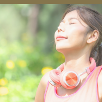 A person stands in the forest with their eyes closed, breathing deeply