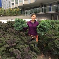 A student holds up their large harvest of kale from UW Farm at Mercer Court. 