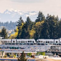 A Sound Transit train at a stop with the Cascade mountain range in the background.