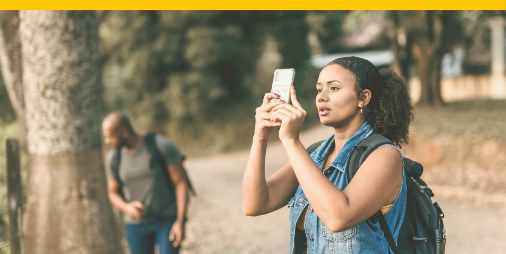 A person takes a photo in a park using a cell phone