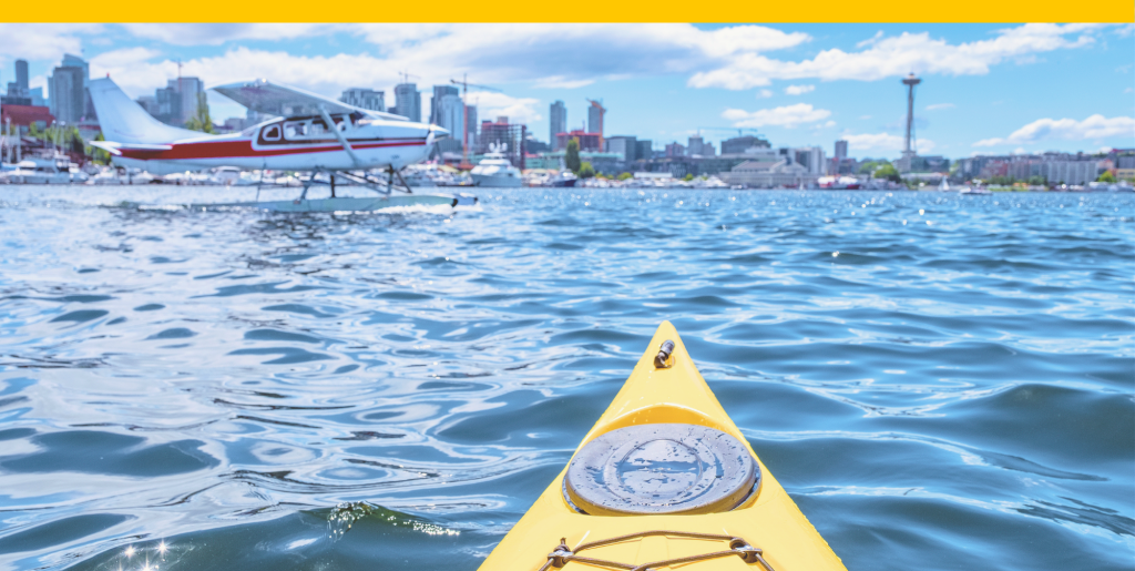 A kayak in Lake Union with the Seattle skyline in the background and a seaplane in the foreground